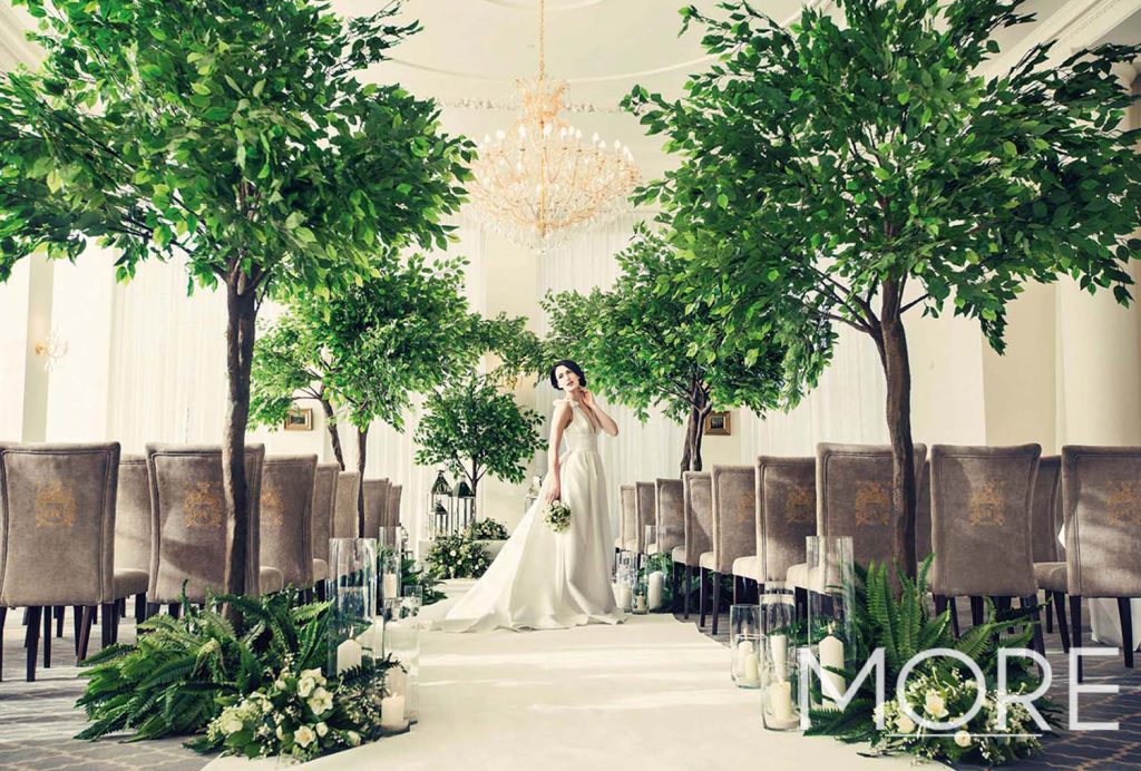Rushton Hall wedding aisle dressing with artificial ficus trees, white carpet, glass vases and chrome lanterns